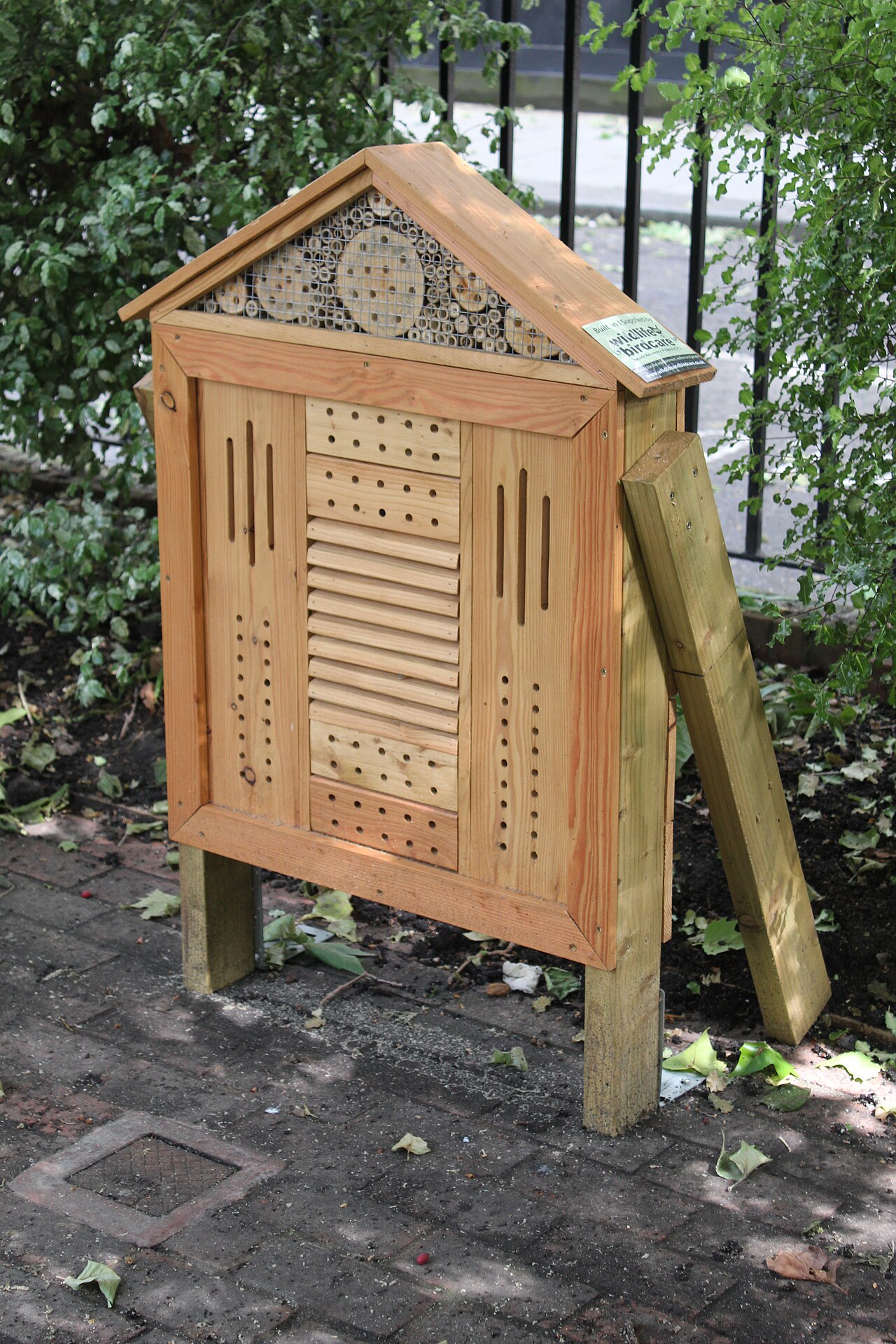 Wooden insect hotel filled with hollow tubes and nesting blocks in a garden