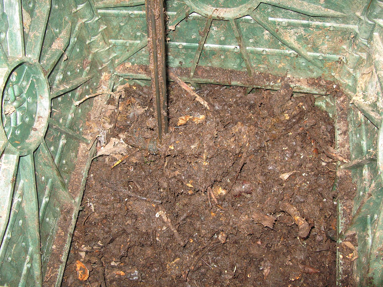 Pitchfork turning and aerating material inside a compost bin